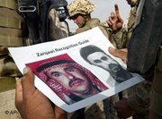 US soldiers looks at a leaflet that pictures Musab al-Zarqawi (photo: AP)