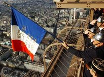 Nationalists dressed in WW II outfits are hoisting the French flag atop the Eiffel Tower (photo: AP)