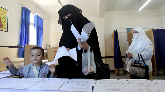 Woman in a Niqab and a boy at the election box (photo: dpa/picture-alliance)