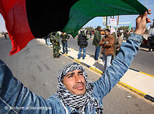 Ein Aufständischer mit libyscher Flagge der prä-Gaddafi-Ära in Ras Lanouf; Foto: dpa