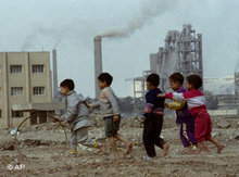 Spielende Kinder in der Nähe eines Industriekomplexes; Foto: AP