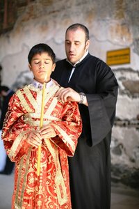 Junge mit Kerze und orthodoxer Priester bei der Zeremonie; Foto: Iason Athanasiadis