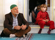 Mann und Kind sitzen in einer Moschee; Foto: dpa