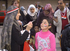 امرأة ترسم العلم المصري على وجه طفلة. حقوق الصورة :دويتشه فيله