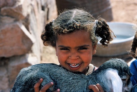Beduinenmädchen spielt mit einer Ziege
