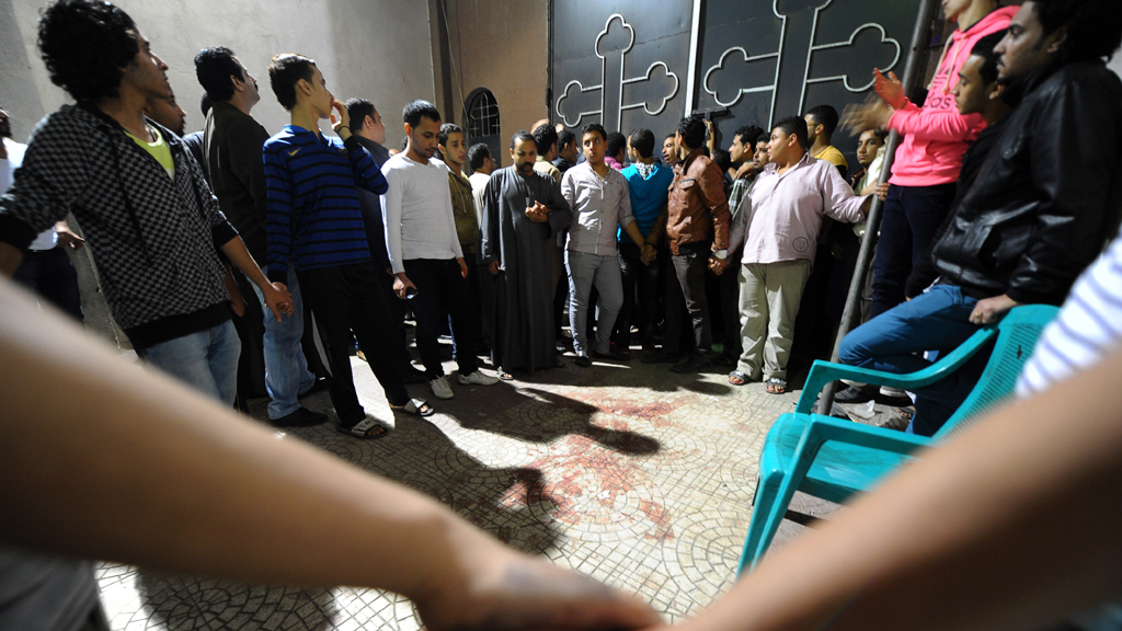 Egyptians gather at a Coptic Christian church in Cairo on 20 October 2013 after gunmen on motorcycles opened fire, killing a woman and wounding several people (photo: AP/Mohsen Nabil)