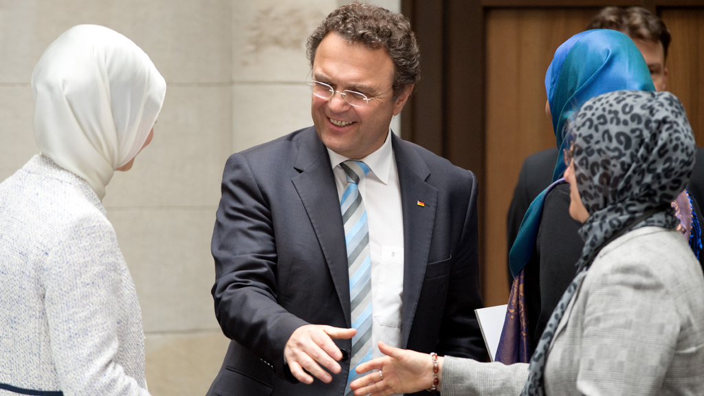 Der frühere Innenminister Hans-Peter Friedrich begrüßt Teilnehmerinnen der Deutschen Islamkonferenz; Foto: dpa/picture-alliance