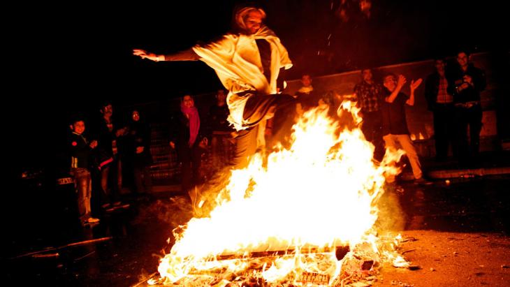 An Iranian woman jumps over fire during the "Chaharshanbeh-Soori" celebratins (photo: Behrouz Mehri/AFP/Getty Images)