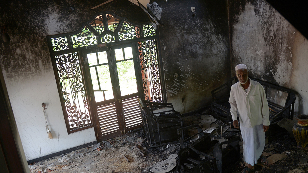 A Sri Lankan resident surveys the damage to a charred Muslim-owned home following clashes between Muslims and an extremist Buddhist group in Alutgama on 17 June 2014 (photo: Lakruwan Wanniarachchi/AFP/Getty Images)
