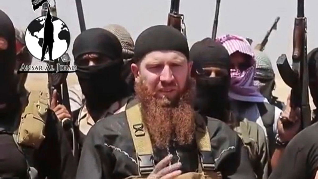 Abu Omar al-Shishani flankiert von maskierten IS-Kämpfern; Foto: AP Photo/militant social media account via AP video