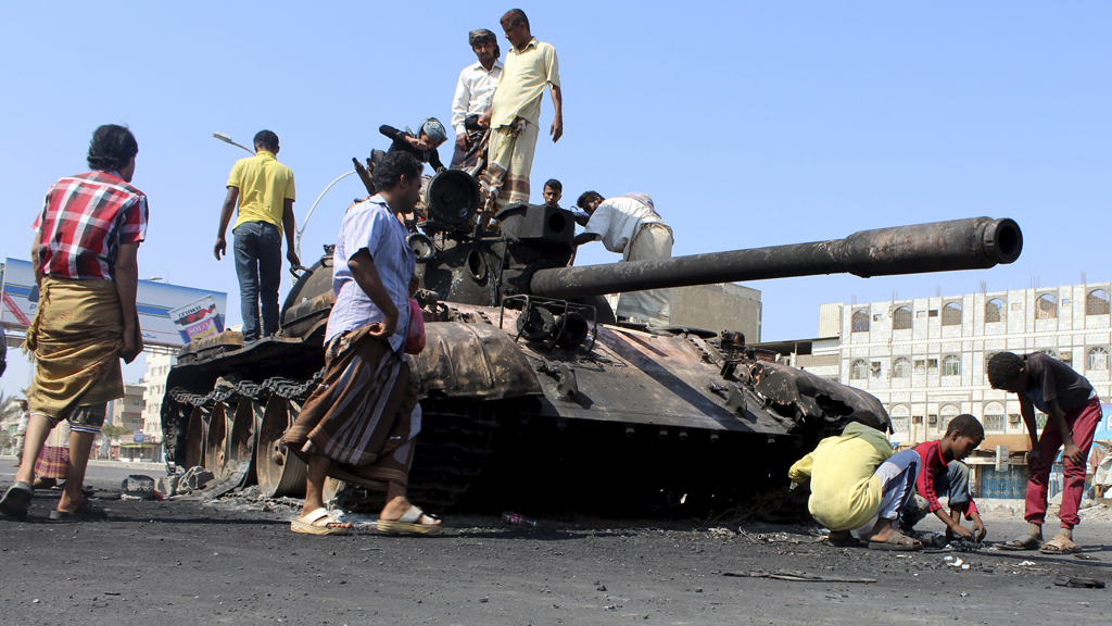 People gather near a tank burnt during clashes on a street in Yemen's southern port city of Aden (photo: Reuters)