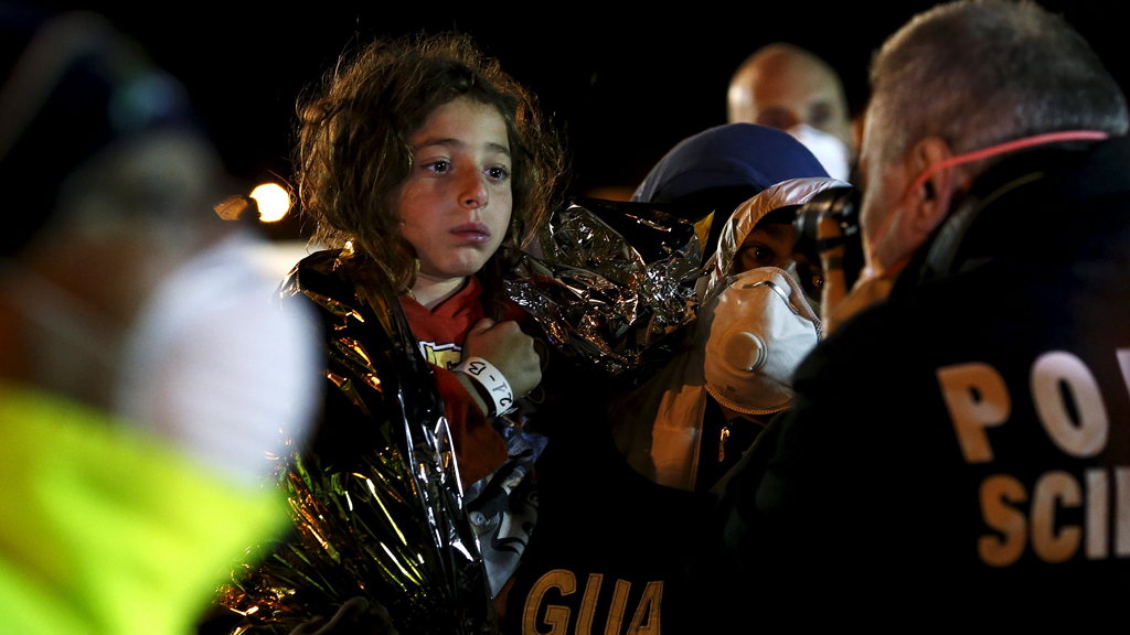 Italian police (right) photograph a child after migrants arrived via boat at the Sicilian harbour of Pozzallo, 19 April 2015 (photo: REUTERS/Alessandro Bianchi)