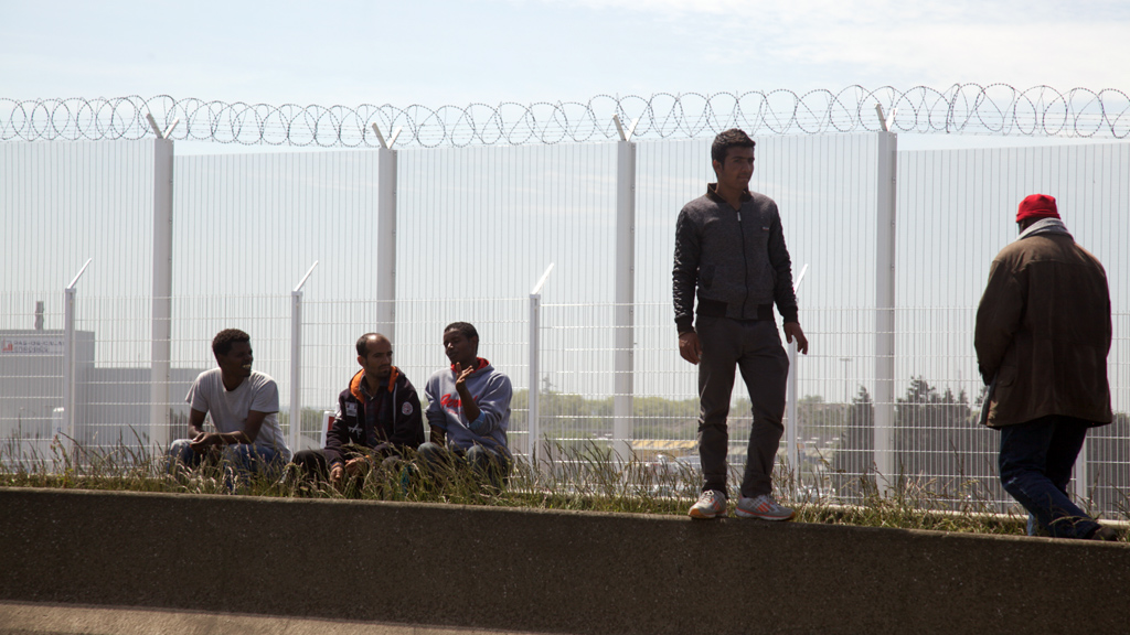Flüchtlinge lehnen am Grenzzaun in der französischen Hafenstadt Calais. Foto: DW/ L. Scholtyssek