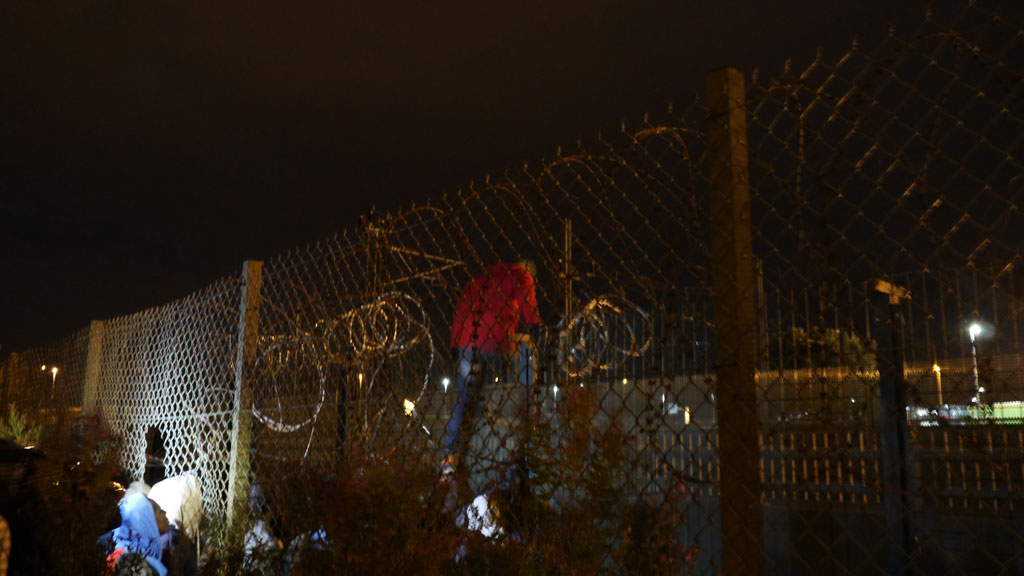 Ein Flüchtling übersteigt einen Sicherheitszaun am Eurotunnel in Calais. Foto: DW/ B. Riegert