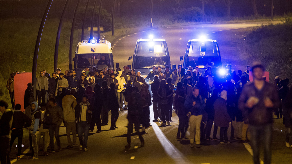 Polizeiwagen eskortieren Migranten vom Eingang des Eurotunnels in der Nähe von Calais. Foto: Getty Images/ AFP/ P. Huguen