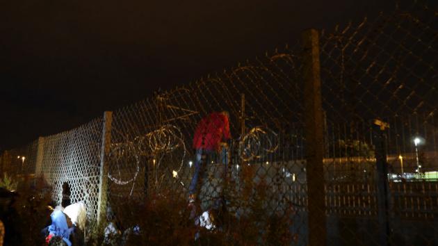 A refugee climbs over a Eurotunnel security fence in Calais (photo: DW/B. Riegert)