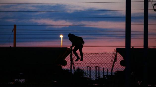 A refugee climbs over a fence near the entrance to the Channel Tunnel (photo: picture-alliance/empics/Y. Mok)