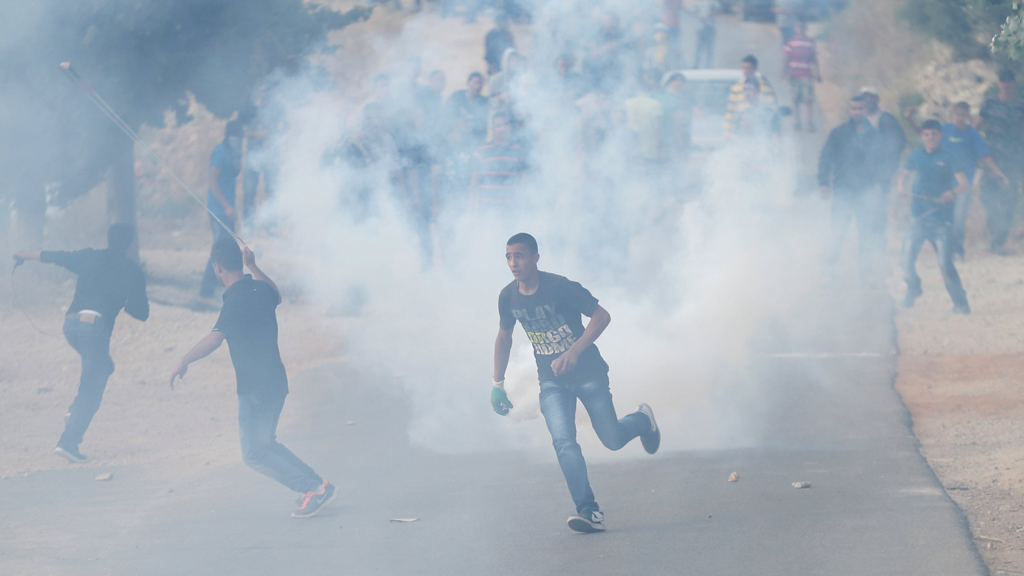 A Palestinian protester runs from tear gas fired by Israeli troops during a protest against the Jewish settlement of Ofra, in the West Bank village of Silwad, near Ramallah, 5 June 2015 (photo: Reuters/Mohamad Torokman)