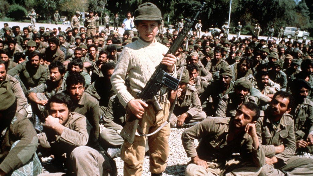Young Iranian boy poses with a machine gun in front of Iraqi POWs in Suze-Desfoul, April 1982 (photo: picture-alliance/image archive)