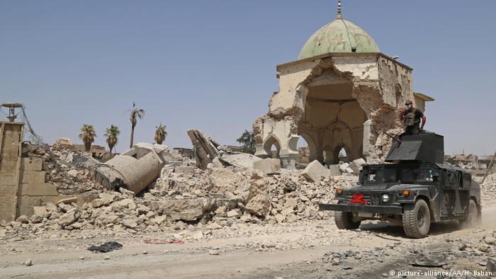 An armoured vehicle drives past a destroyed building in Mosul (photo: picture-alliance/AA/H. Baban)