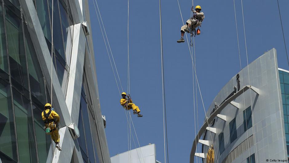 Nepalese window cleaners abseil down the facade of Tornado Tower (left) in Doha, Qatar (photo: Getty Images)