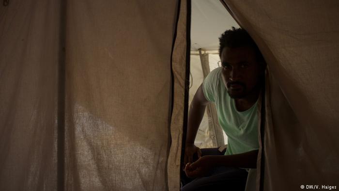 An Ethiopian asylum-seeker peers out of a tent on Lesbos