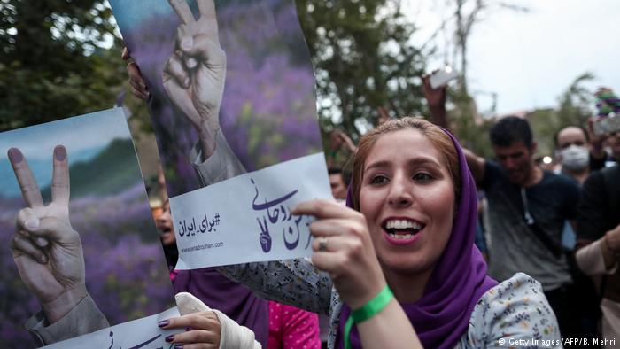 Supporters of newly re-elected Iranian President Hassan Rouhani hold placards as they celebrate his victory in Tehran