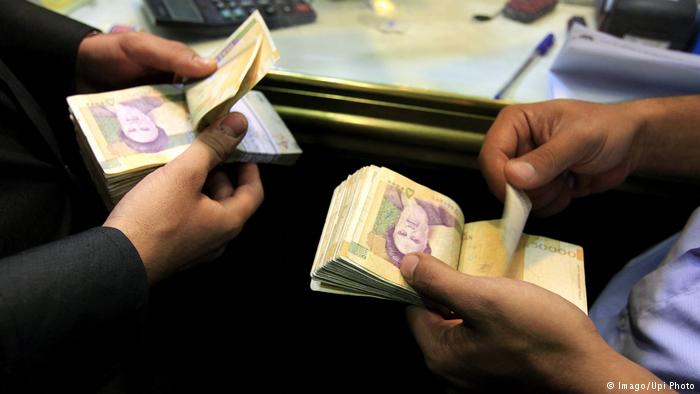 Iranian men count their 50,000 rial banknotes