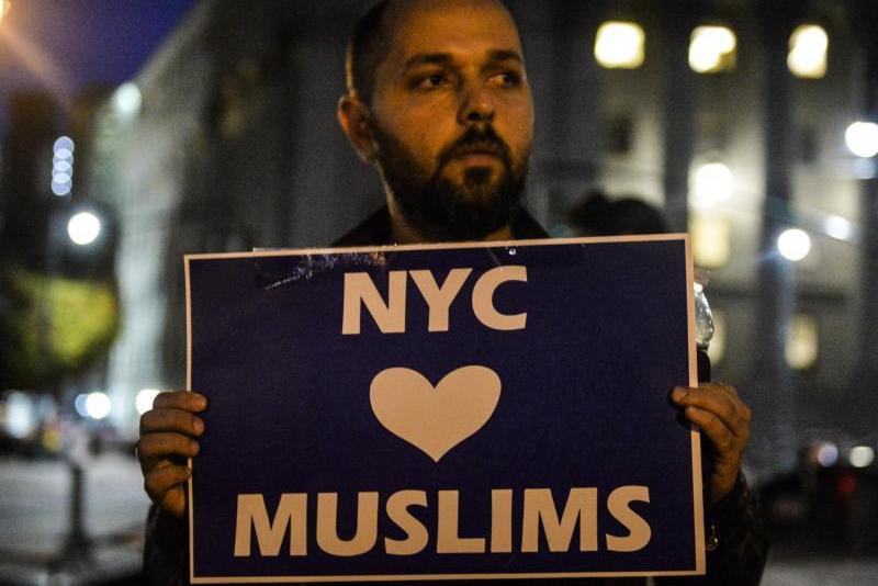 Muslimischer Mann aus Manhattan hält während einer Nachtwache für die Terroropfer von New York ein Schild mit der Aufschrift "New York City liebt Muslime" hoch; Foto: dpa