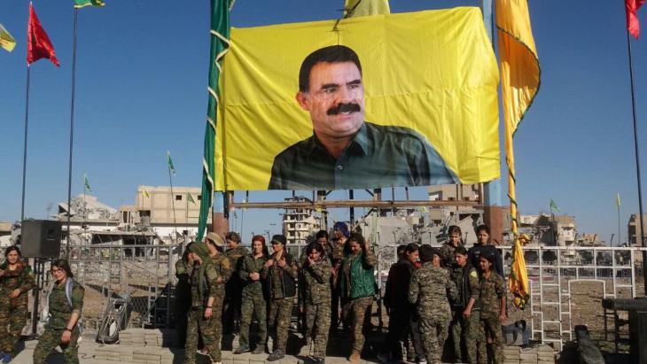 Syrian Democratic Forces units gather below a banner of PKK leader Ocalan following the fall of Raqqa on 19 October 2017 (photo: AFP/Getty Images)