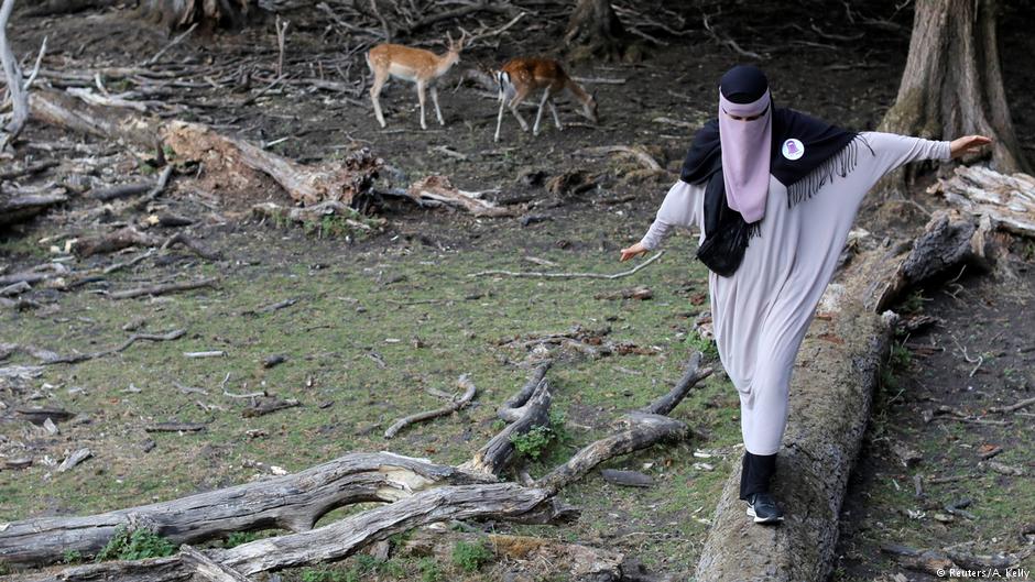 Meryem, 20, a wearer of the niqab and a member of the group Kvinder I Dialog (Women In Dialogue), walks across a log at Dyrehaven, a deer petting park, in Aarhus, Denmark, 27 July 2018 (photo: Reuters/Andrew Kelly)