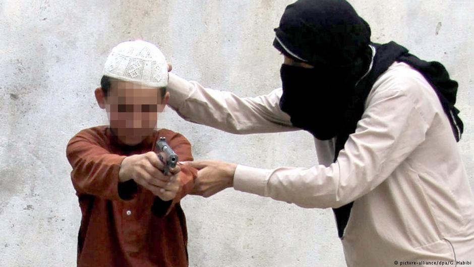 رجل من تنظيم الدولة الإسلامية "داعش" يدرب طفلا على القتال.
