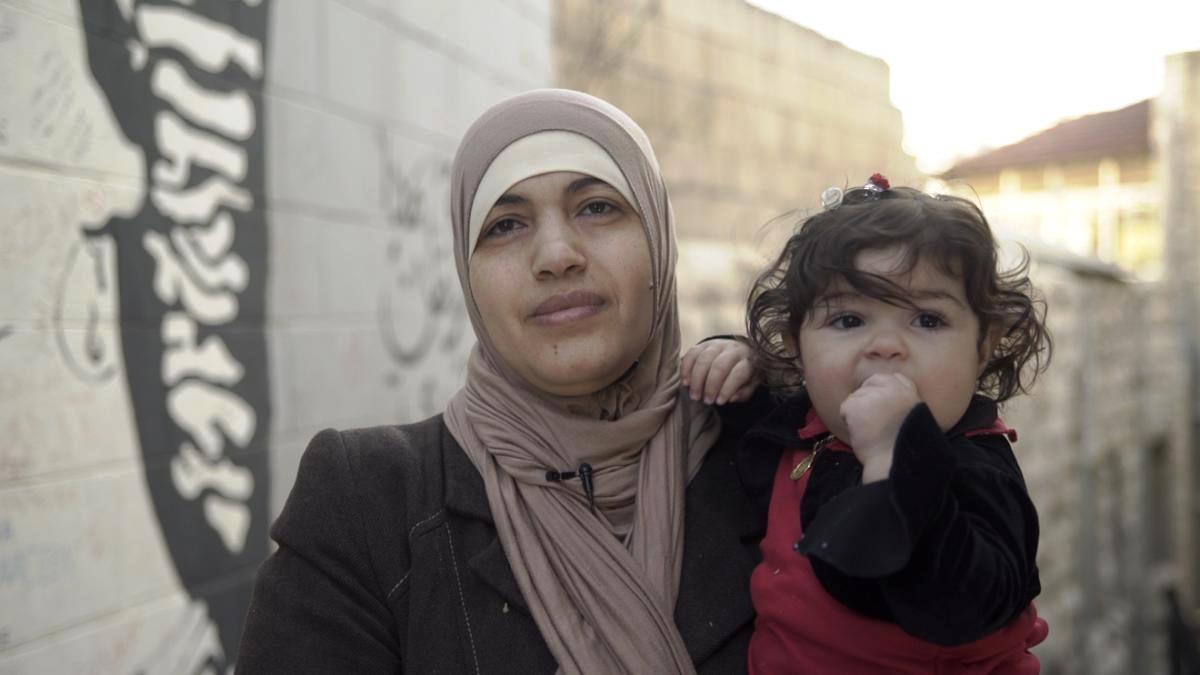   امرأة أردنية متزوجة من رجل أجنبي، تحمل طفلتها، وهي واحدة من أبنائها الأربعة غير الحاصلين على الجنسية الأردنية. الصورة في 9 فبراير/شباط 2018 في عمان، الأردن.  © 2018 أماندا بايلي لـ هيومن رايتس ووتش 