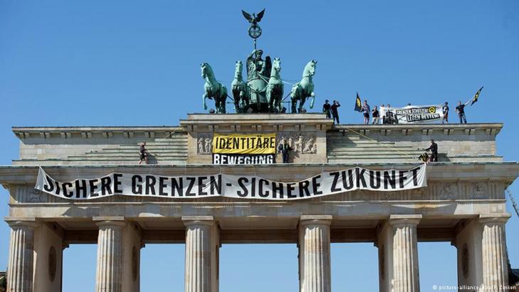 Members of the Identitarian movement hang banners from Berlinʹs Brandenburg Gate in August 2016 (photo: picture-alliance/dpa/P. Zinken)