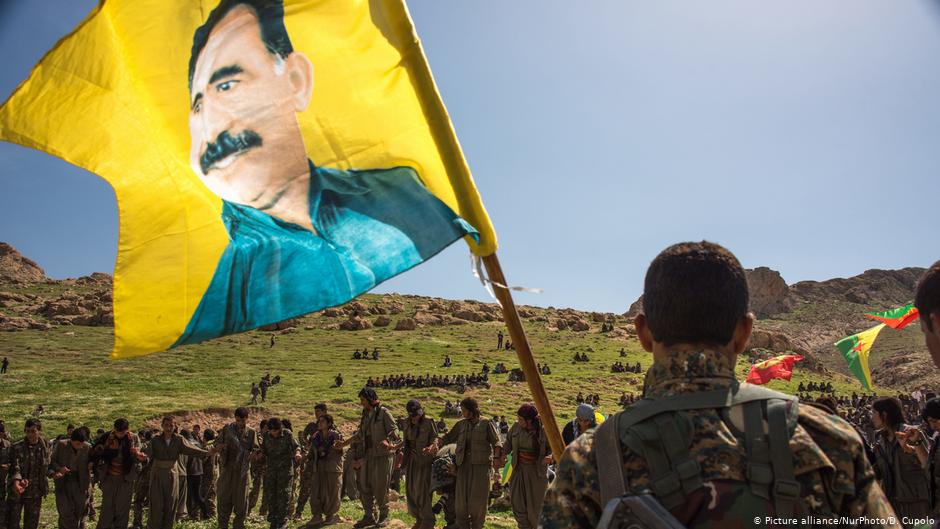 Kurdische Milizen mit einer Fahne des inhaftierten PKK-Führers Abdullah Öcalan; Foto: picture-alliance/NurPhoto/D. Cupolo