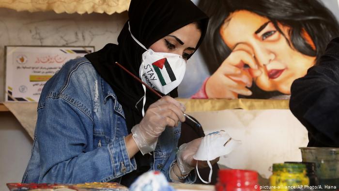 Palestinian artist Samah Saed decorates a protective face mask (photo: picture-alliance/AP Photo/A. Hana)