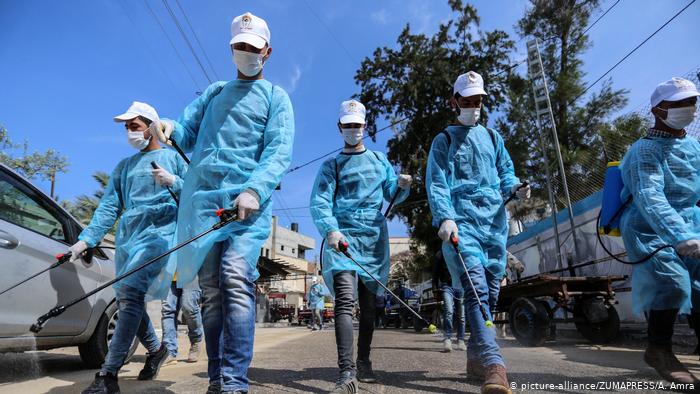 Palestinian workers spray disinfectant as a preventive measure amid fears of the spread of the coronavirus disease (photo: picture-alliance/ZUMAPRESS/A. Amra)