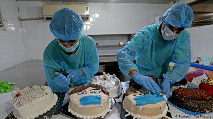 Palestinian bakers decorate cakes shaped like faces wearing protective masks (photo: Reuters/I. Abu Mustafa)