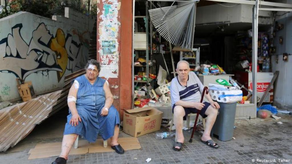 Ein älterer Mann und eine ältere Frau, sie mit Binden und Pflastern, sitzen vor ihrem zerstörten Lebensmittelgeschäft Reuters/A. Taher)