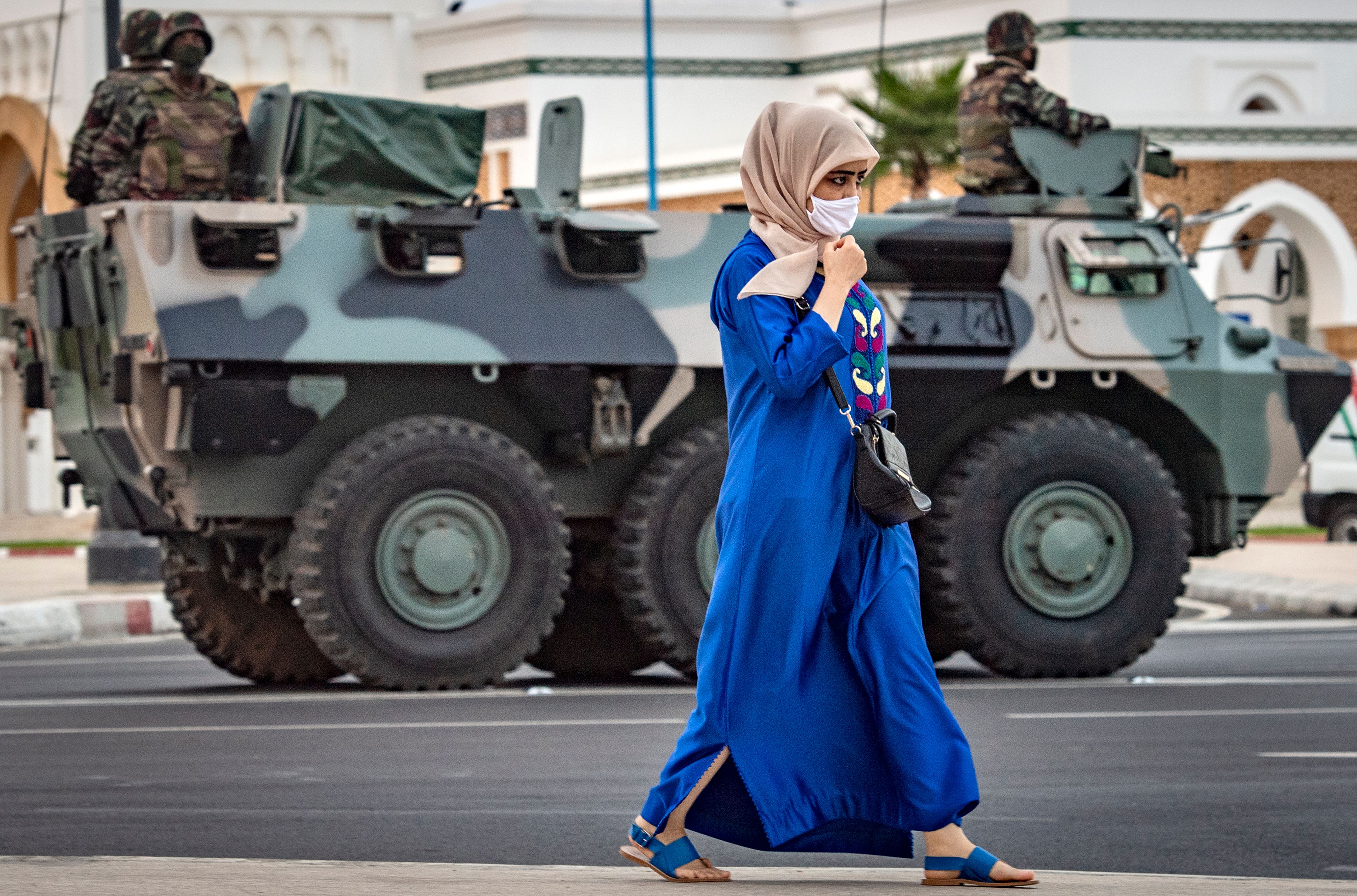 A woman walks past a tank and soldiers on a street in Tangier, Morocco, on 11 August 2020  (photo: FADEL SENNA/AFP)