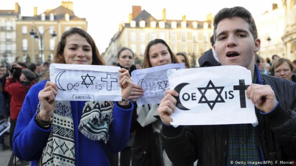 People hold signs reading 'co-exist' at a rally in Rennes (photo: Getty Images/ AFP/ J.Monier)