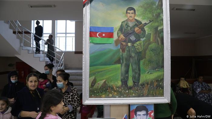 Women and children in a room and a large painting of a soldier (photo: Julia Hahn/DW)