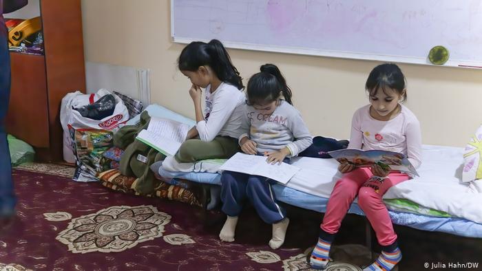 Three young girls seated on a cot, reading, in the Azerbaijani town of Barda (photo: Julia Hahn/DW)