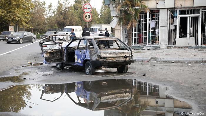 A burned-out car in front of a building with a shop that has been destroyed in Barda (photo: Julia Hahn/DW)