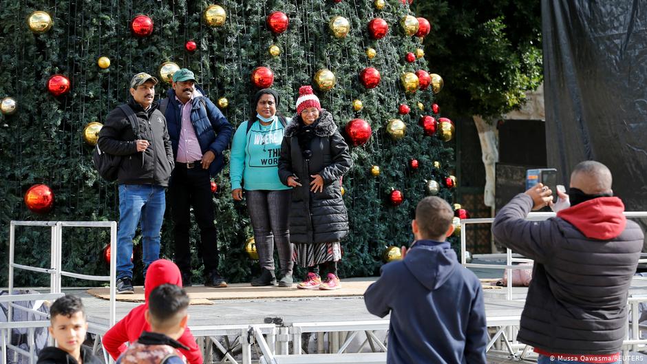 مسيحيون فلسطينيون يلتقطون صورا تذكارية أمام شجرة عيد الميلاد 2020 في بيت لحم.