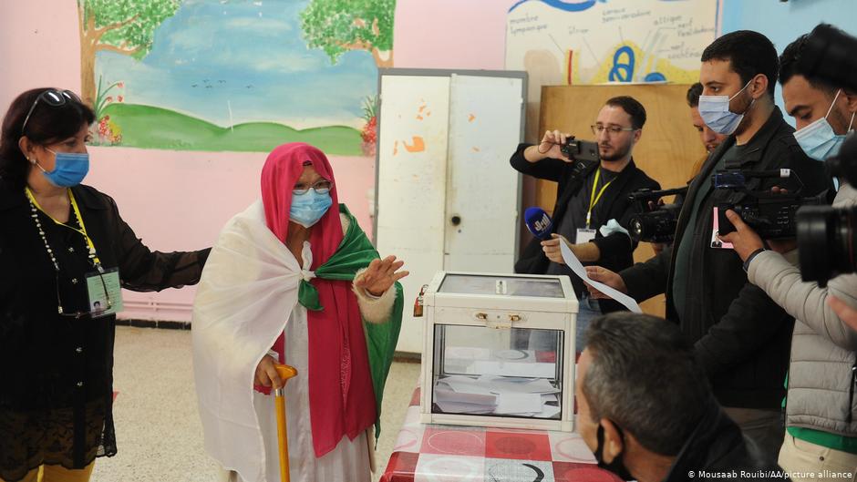 Elderly woman draped in the Algerian flag casts her vote in the Algerian constitutional referendum on 1 November 2020 (photo: Mousaab Rouibi/AA/picture-alliance)