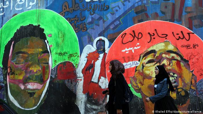 Ein Graffiti zeigt den Blogger Khaled Said mit geschlossenen Augen. Daneben ist eine Frau gemalt die eine rote Rose in der Hand hält. Foto: picture-alliance/dpa/Khaled Elfiqi