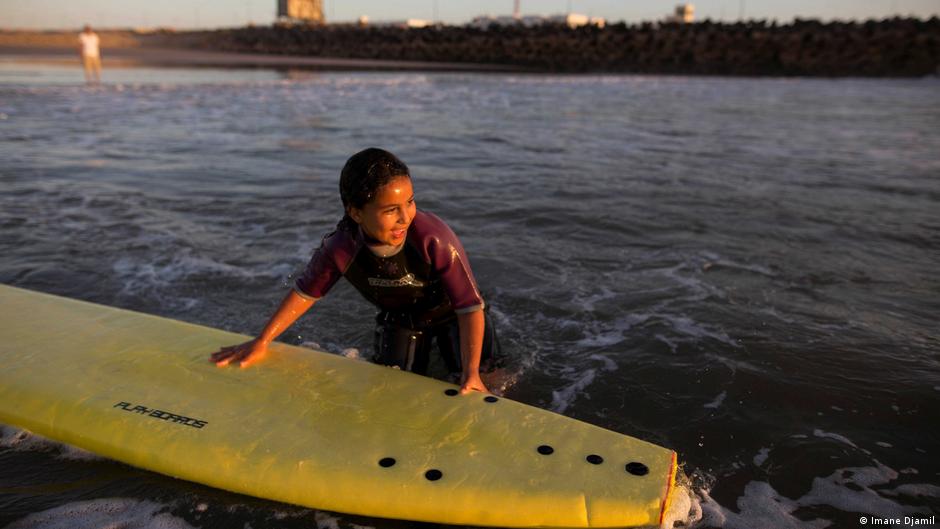 Eine Schülerin hält sich während einer kostenlosen Surfstunde an einem Surfbrett fest. Foto: Imane Djamil