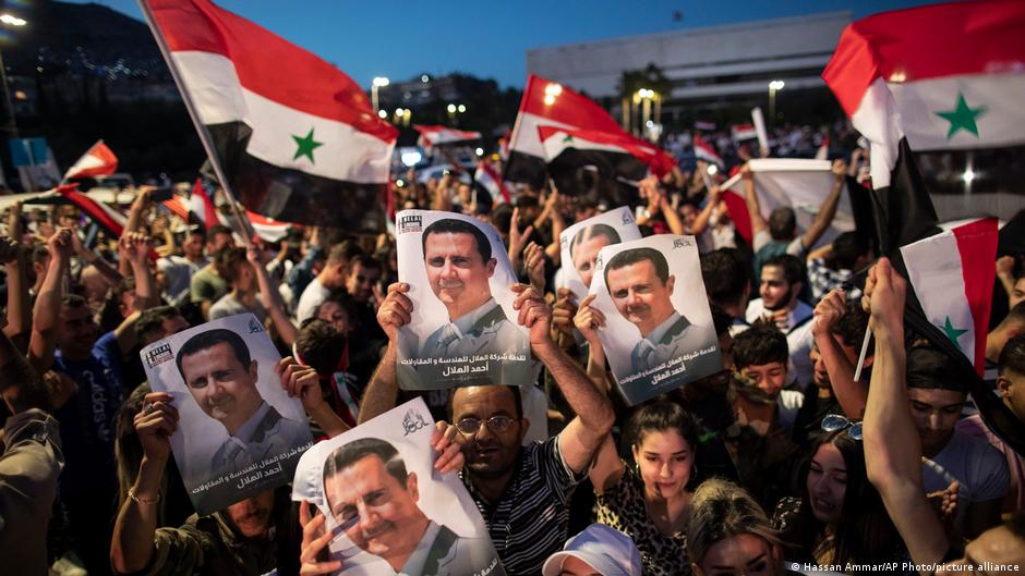 ابتهاج بعض الناس بصورة رئيس النظام السوري بشار الأسد. Foto: Hassan Ammar/AP Photo/picture-alliance