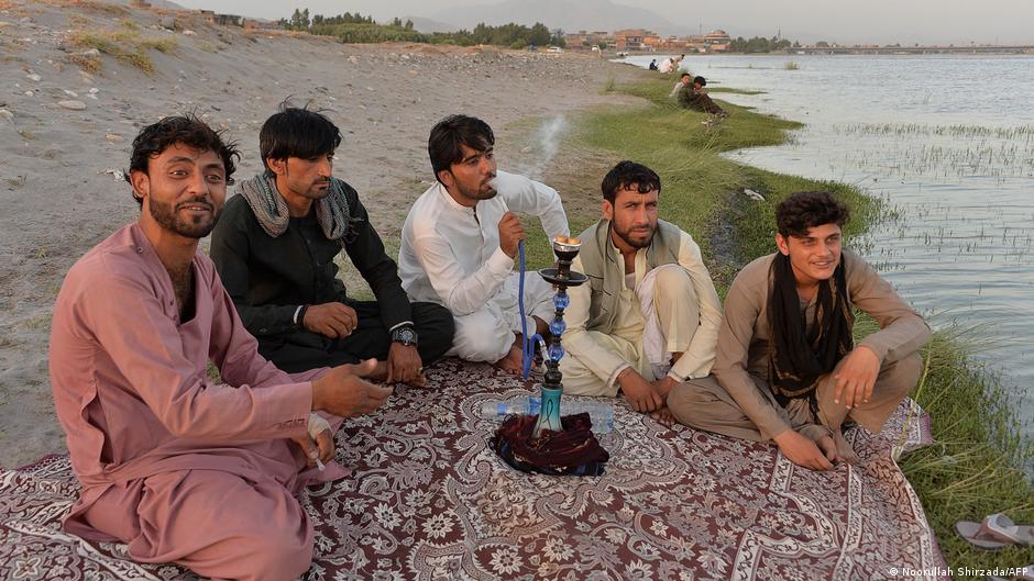 In this photo taken on 9 June 2021, men smoke a 'hookah' water pipe along a river on the outskirts of Jalalabad (photo: Noorullah Shirzada/AFP)